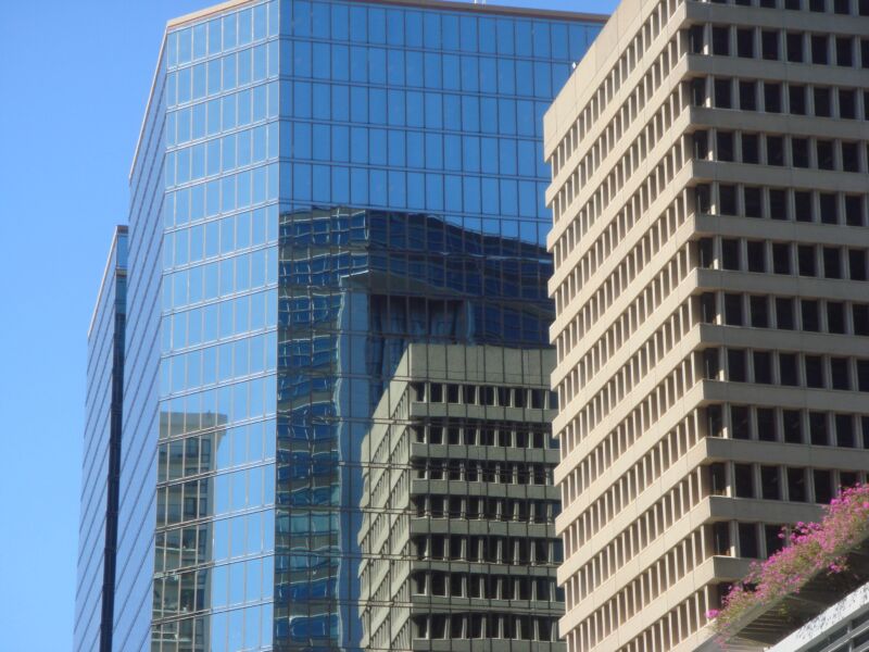 Glashochhaus spiegelt ein benachbartes beiges Betongebäude mit Rasterfenstern, Fotografie aus der Serie «Honolulu»