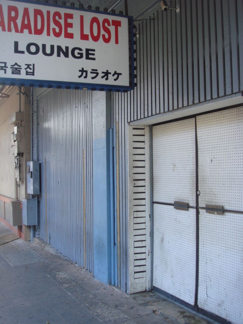Leuchtschild «Paradise Lost Lounge» über verschlossenen Blech- und Lochtafeltüren an einem Gehsteig, Fotografie aus der Serie «Honolulu»