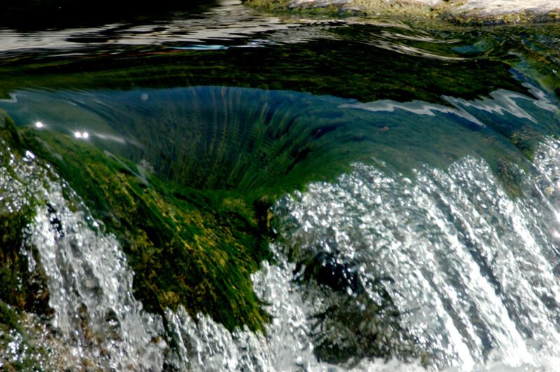Wasser stürzt über eine moosgrüne Felsstufe und bildet einen glitzernden kleinen Fall, Fotografie aus der Serie «An ligurischen Flüssen und Bächen»